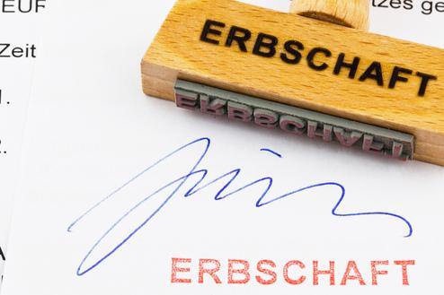 Holzstempel mit Aufschrift "ERBSCHAFT" auf einem Dokument, das eine Unterschrift und den Stempelabdruck zeigt.